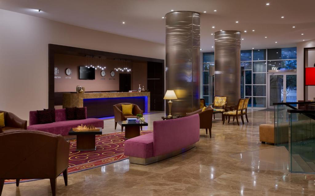 un vestíbulo de un hotel con mesas y sillas púrpuras en Renaissance by Sulo en Aktau