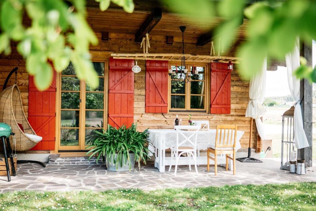 ein Haus mit roten Türen und einem weißen Tisch und Stühlen in der Unterkunft Gemütliches Ferienhaus in Feistritz Ob Bleiburg mit Garten, Terrasse und Grill in Feistritz ob Bleiburg