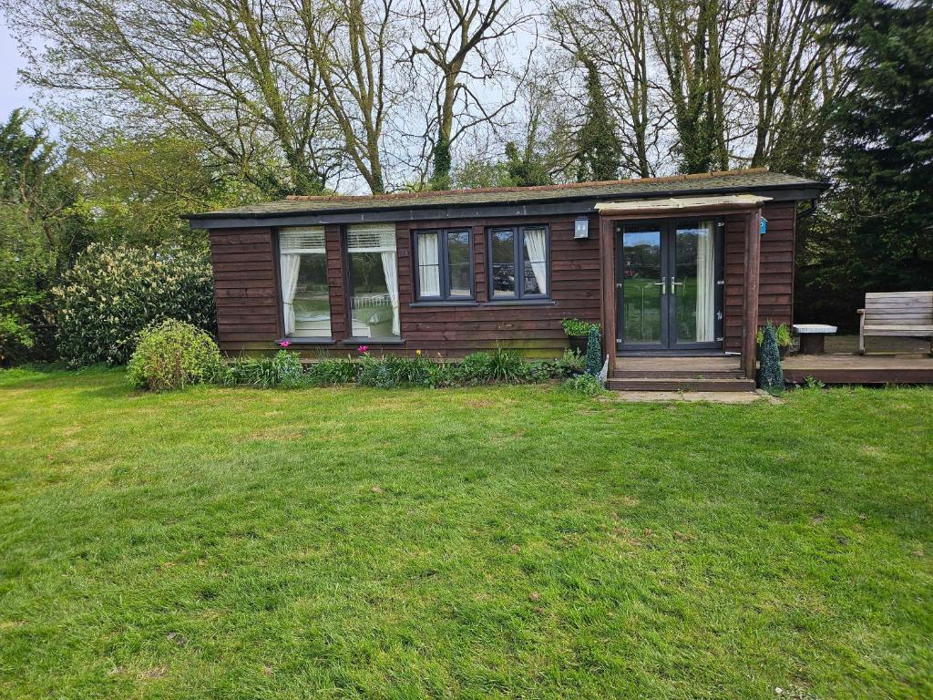a small house with a bench in a yard at Remarkable 1-Bed Cabin in Dunmow in Great Dunmow