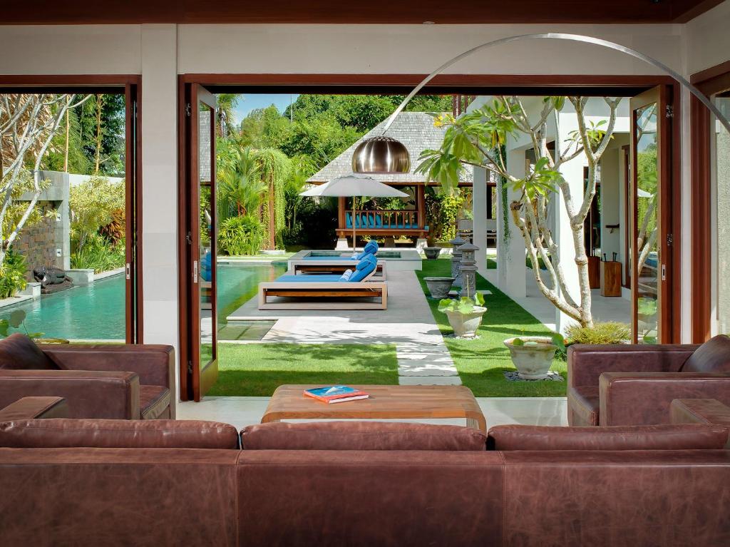 a living room with a couch and a pool at Villa Joss Seminyak by Nagisa Bali in Seminyak