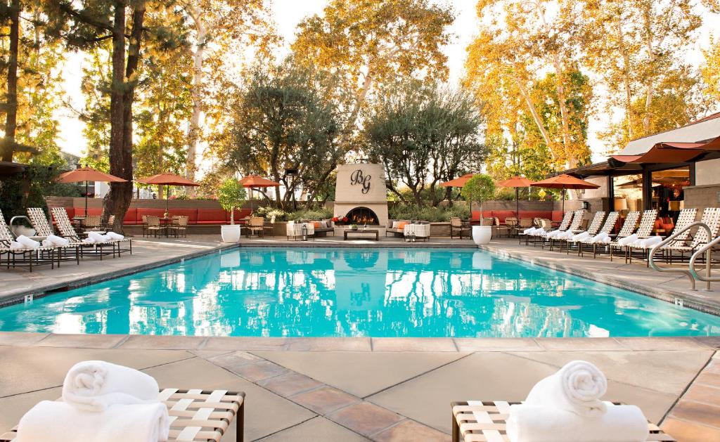 einen Pool in einem Hotel mit Stühlen und einem Kamin in der Unterkunft The Garland in Los Angeles