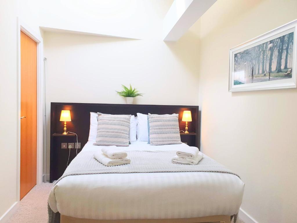 a bedroom with a large bed with two towels on it at THE PENTHOUSE AT REGENT HOUSE Light and airy top floor with lift access 1 bedroom en-suite luxury apartment ULTRA CENTRAL LOCATION in Harrogate