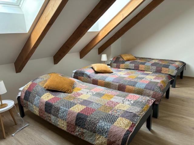 Duas camas num quarto no sótão com vigas de madeira em Apartman Detvianka 2 em Detva