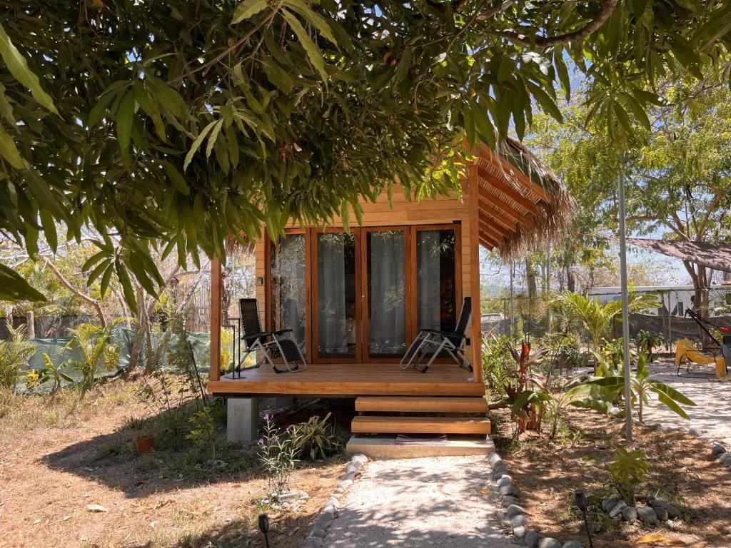 una casa pequeña con dos sillas sentadas en un porche en Naturnahe Cabina Playa Hermosa, Santa Teresa en Santiago