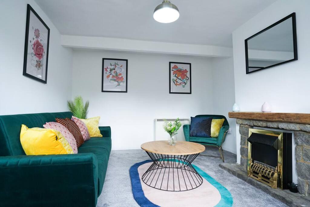 - un salon avec un canapé vert et une cheminée dans l'établissement Serene 3BR Cottage Escape: Parking, Kitchen, Wi-Fi, à Northampton