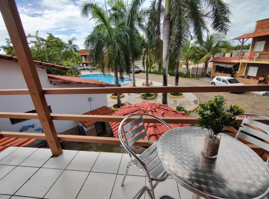 balcón con mesa, sillas y piscina en Chalé em Porto dos Lençóis Residence, en Barreirinhas