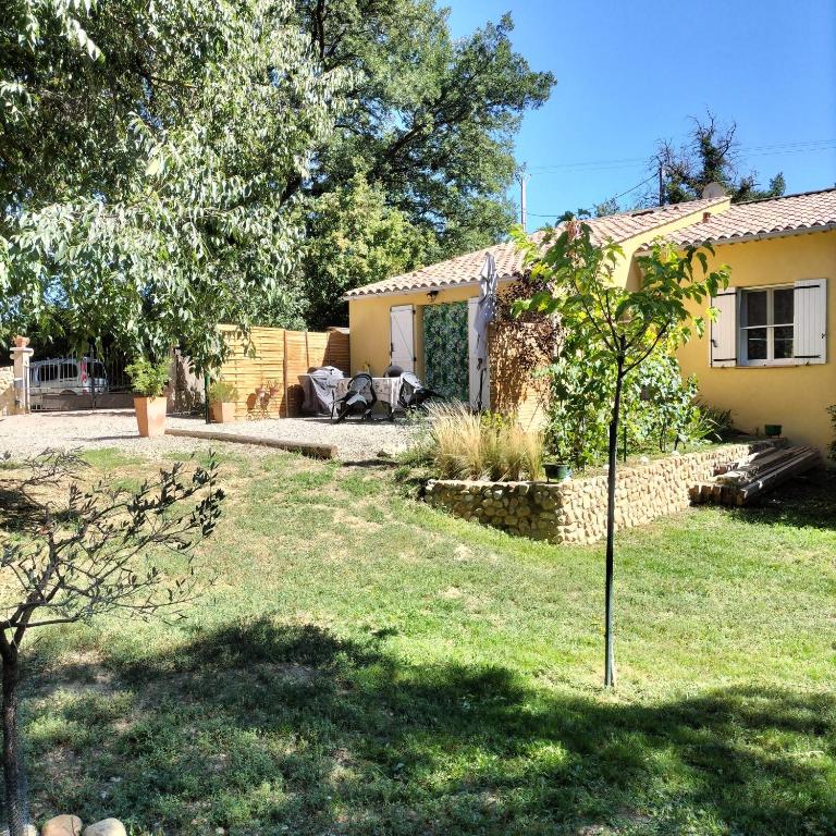 arrière-cour d'une maison avec un arbre dans la cour dans l'établissement Gîte les Romarins, à Montagnac