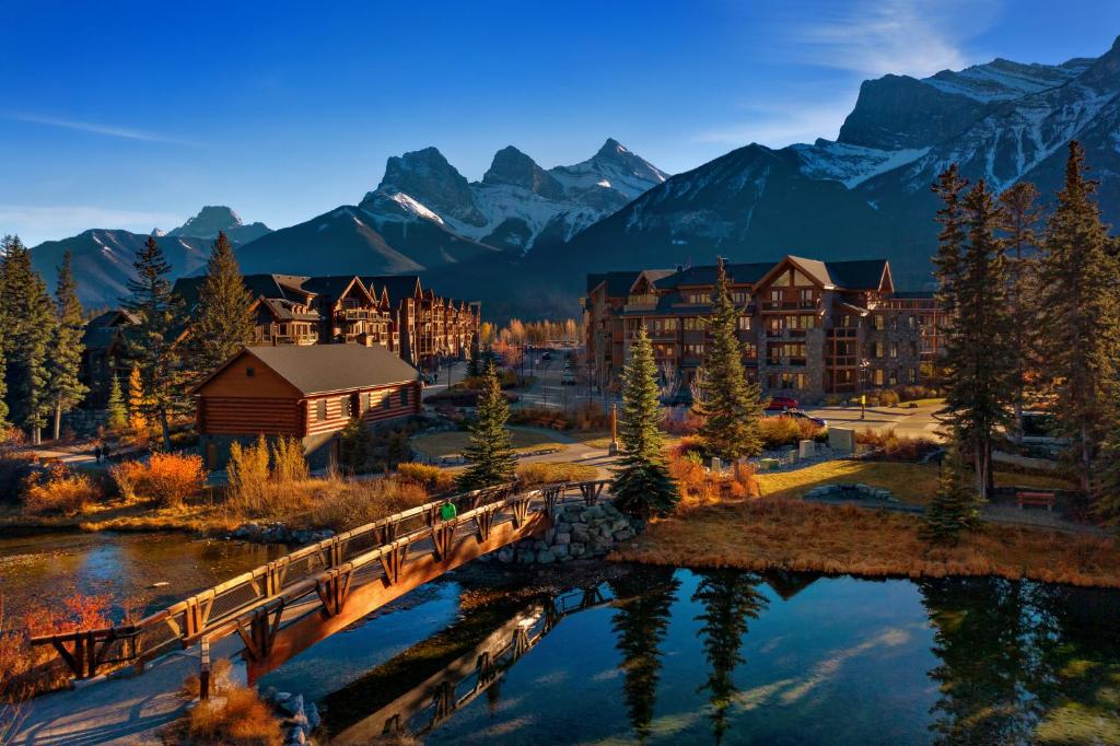 a resort with a bridge over a river and mountains at Spring Creek Vacations in Canmore