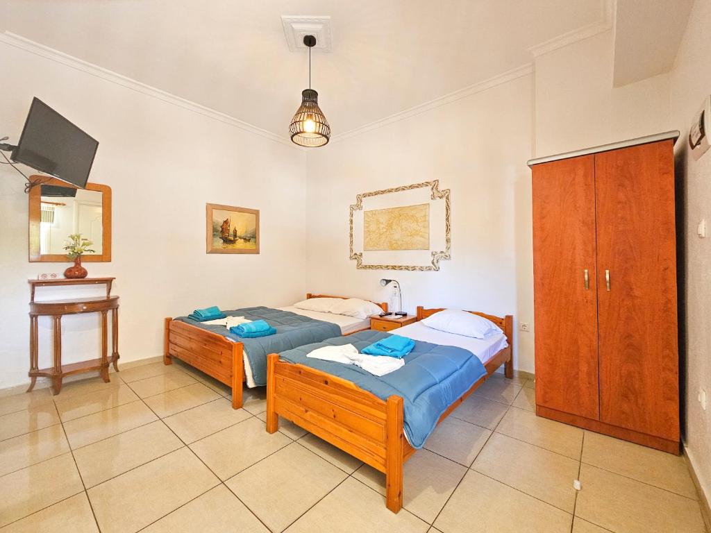 a bedroom with two beds and a desk and a tv at Hotel Exarhos in Paralia Katerinis