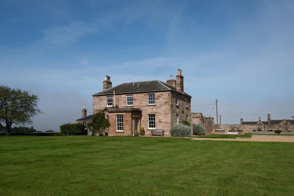 an old stone house with a large grass field at Seaview House in Cockburnspath