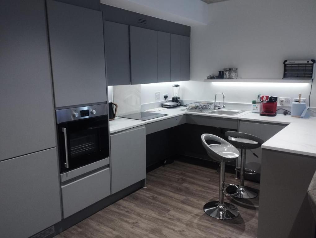a kitchen with white cabinets and two stools in it at Immaculate 3-Bed Apartment Homes in London in London