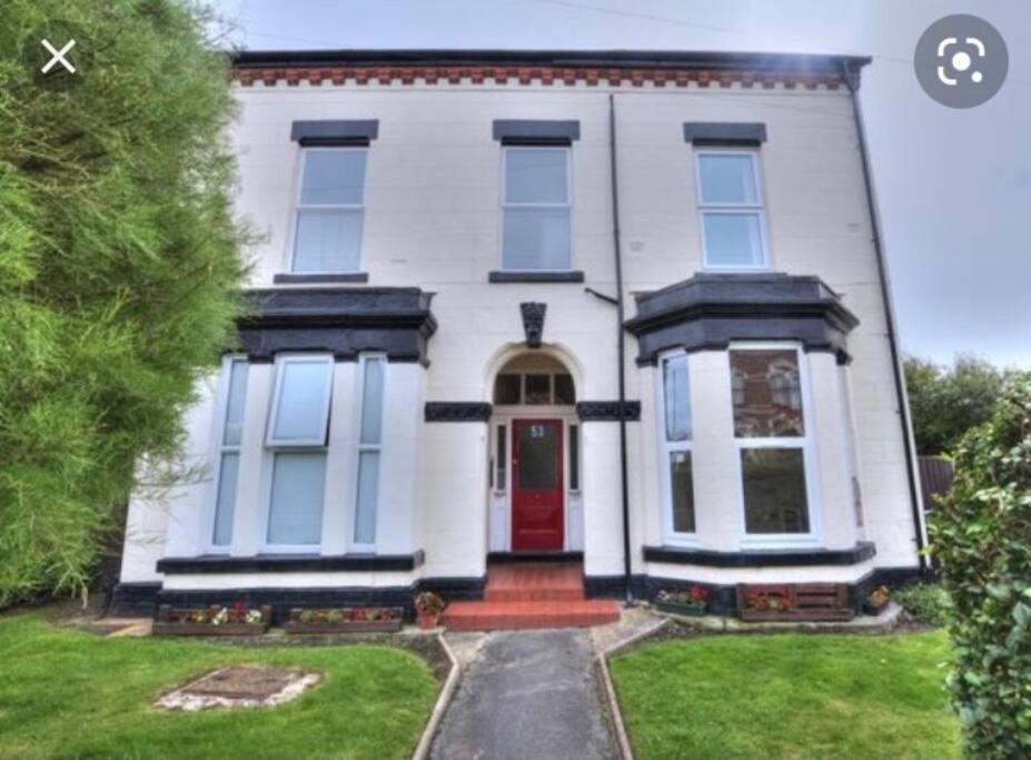 une maison blanche avec une porte rouge dans l'établissement Crosby lovely refurbished flat, direct garden access; Wifi, à Crosby