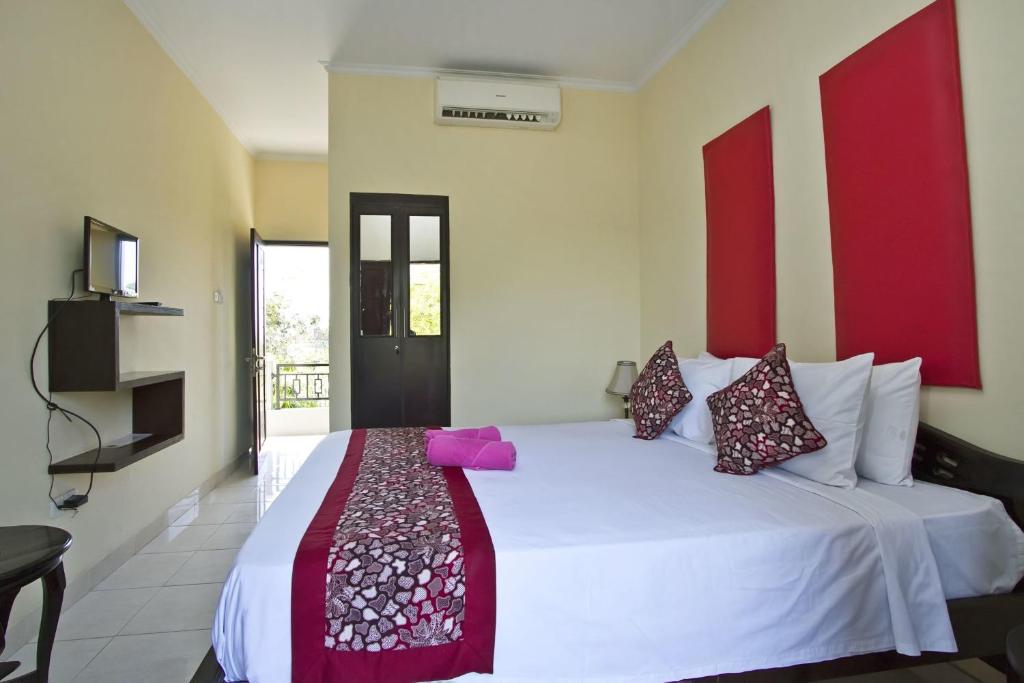 a bedroom with a white bed with red accents at Ramantika Bali House in Jimbaran