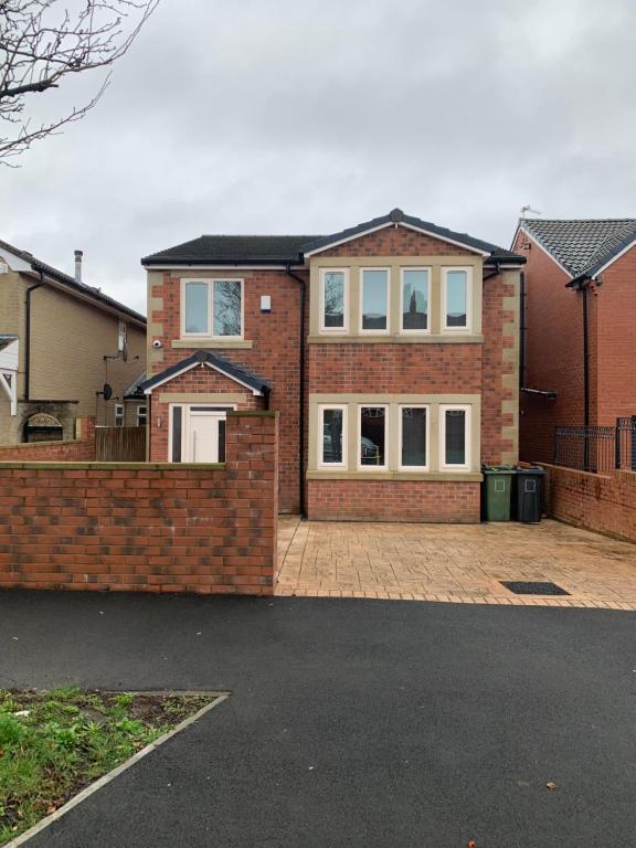 uma casa de tijolos vermelhos com janelas brancas e uma entrada em New Build 4 bed Det House in Yorkshire Nr Leeds em Batley