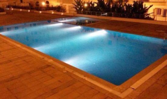 een groot zwembad met blauwe verlichting bij Appartement neuf avec piscine in Zemmour Touirza