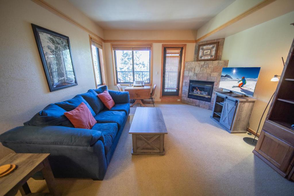 ein Wohnzimmer mit einem blauen Sofa und einem Kamin in der Unterkunft Slopeside 2773a in Keystone
