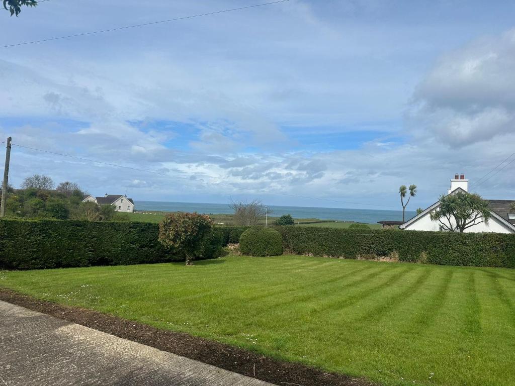 a yard with a green lawn with the ocean in the background at Ocean View in Bushmills