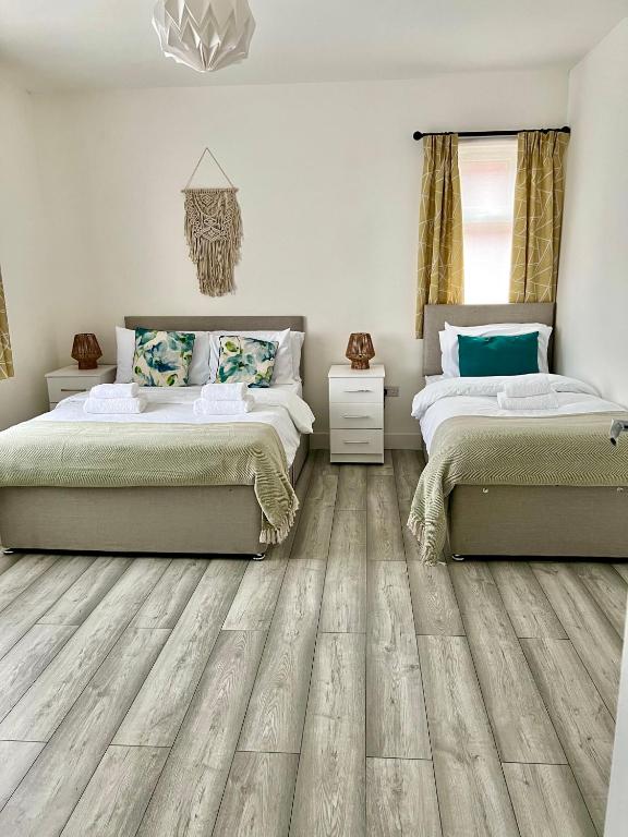 2 letti in una camera da letto con pavimenti in legno di Luton flat with parking a Luton