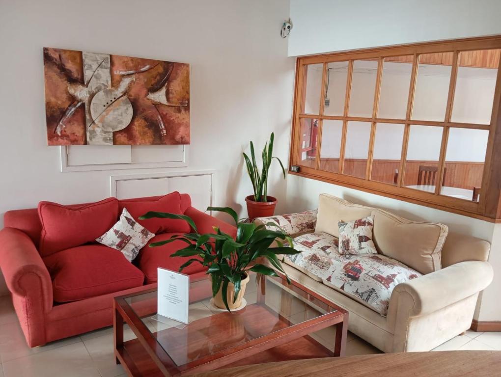 sala de estar con sofá rojo y mesa de cristal en Hotel Palermo Quintero en Quintero