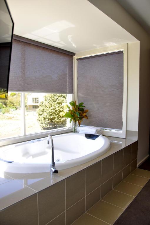 a bathroom with a large white tub and a window at Daylesford Spa Villa One in Daylesford