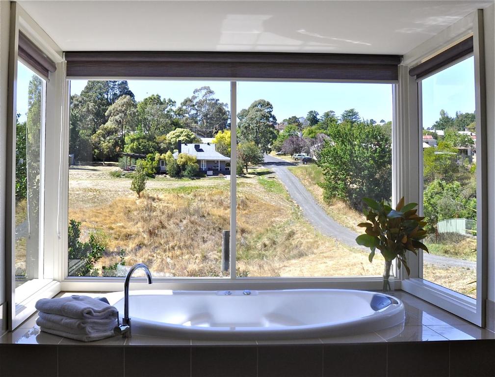 a bath tub in front of a large window at Daylesford Spa Villa One in Daylesford