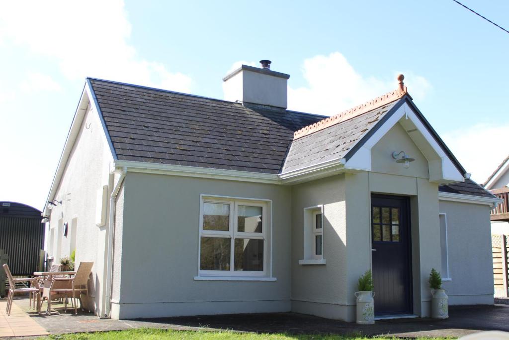 una pequeña casa blanca con techo negro en Heather Cottage and Shepherds Hut en Knock