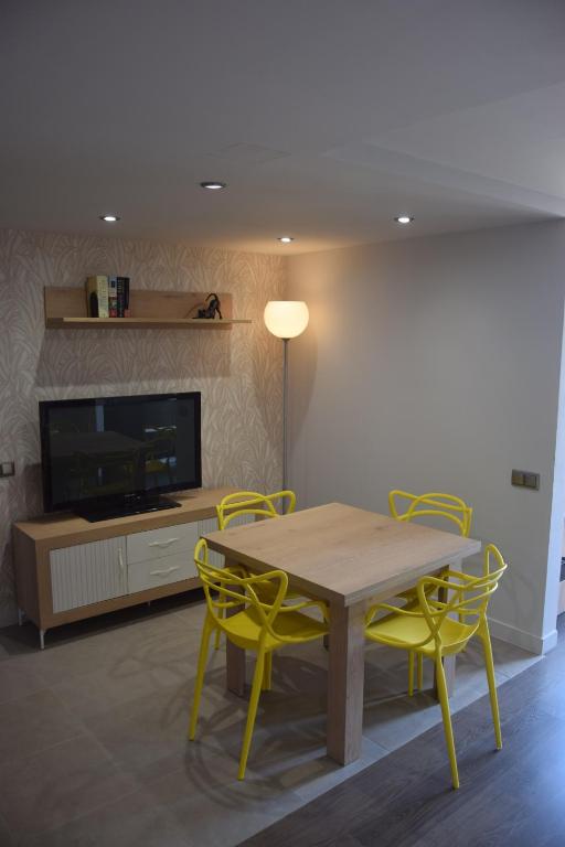 a dining room with a table and yellow chairs at Apartament Sant Jordi in Sant Joan de Vilatorrada