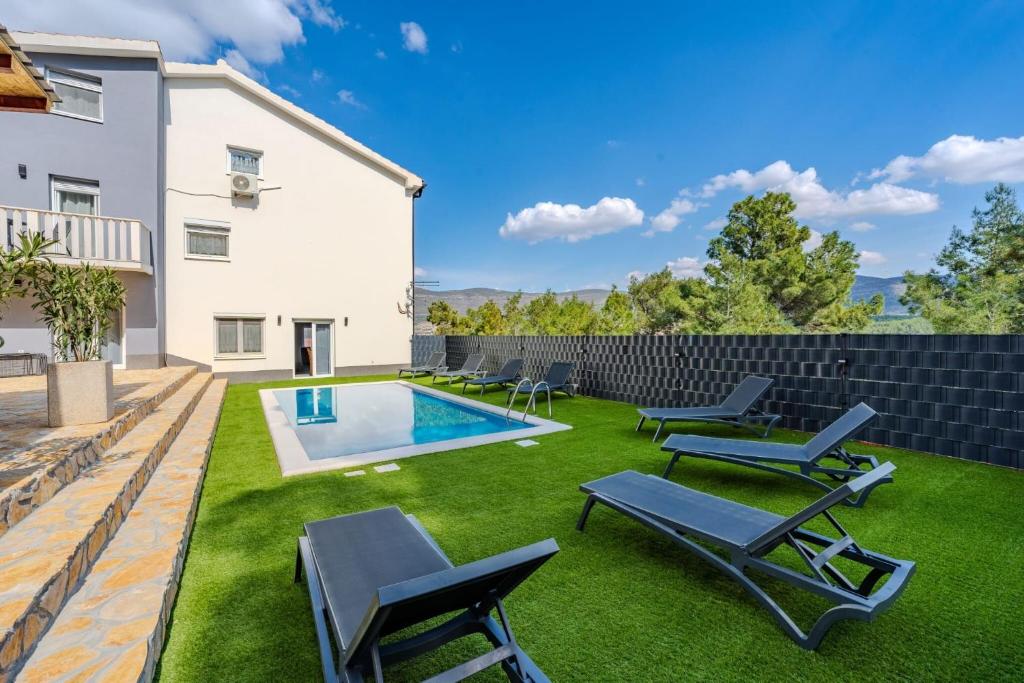 un patio trasero con piscina y tumbonas en Villa Ivanovi Dvori, en Donji Karin