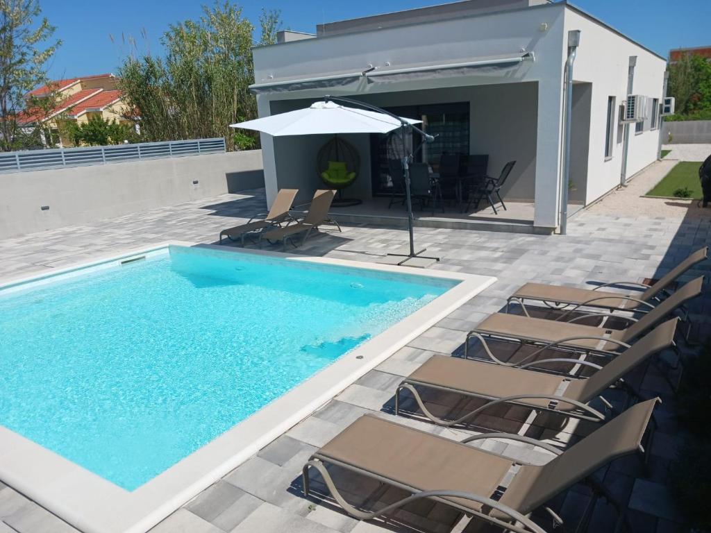 uma piscina com cadeiras e um guarda-sol em Kuća za odmor Sara em Privlaka