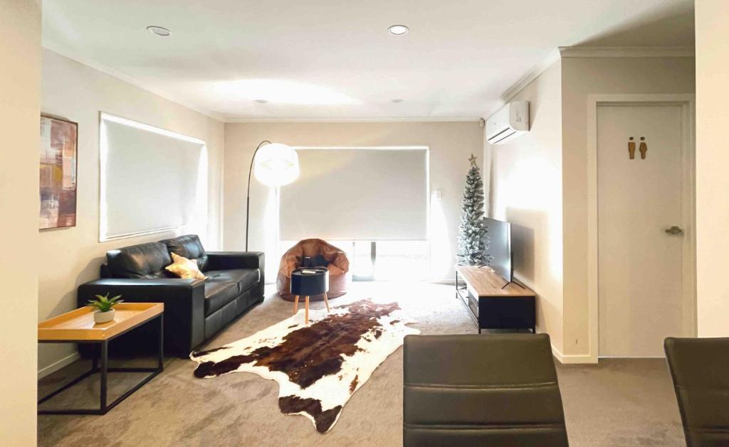 uma sala de estar com um sofá preto e uma mesa em 4 En-suite Rooms Town House em Hamilton