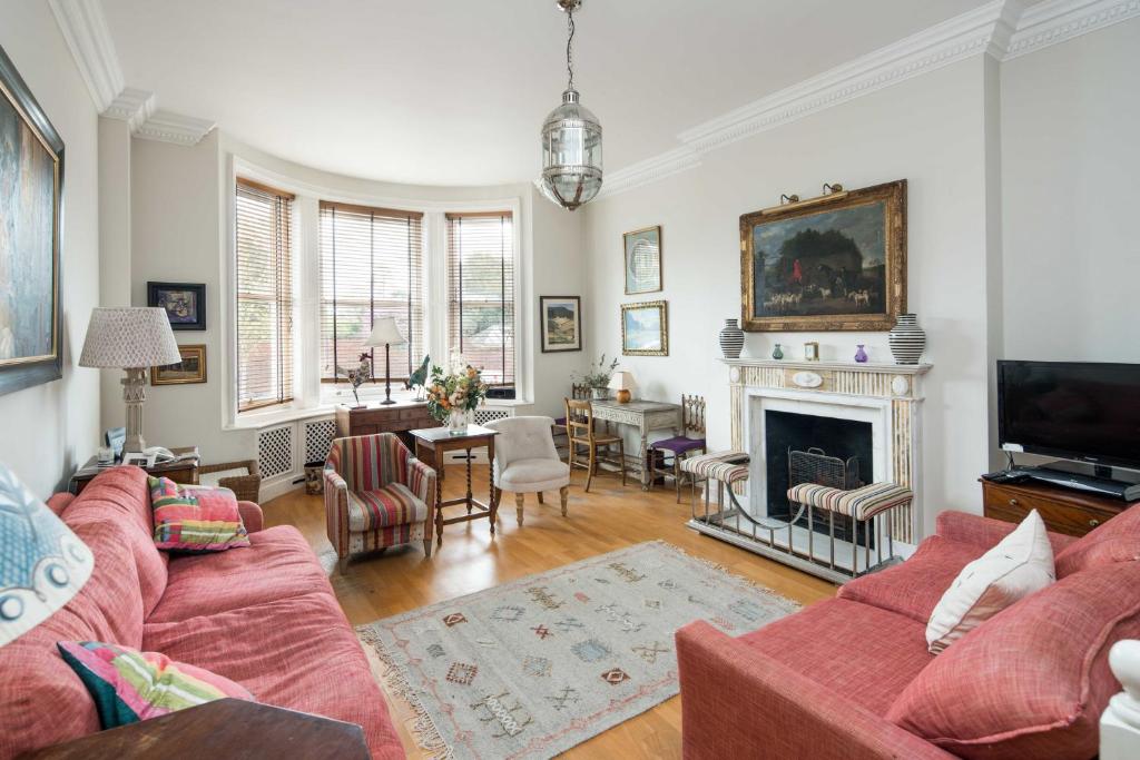 a living room with a red couch and a fireplace at Elegant 2-Bed Duplex with Patio nr Battersea Park in London