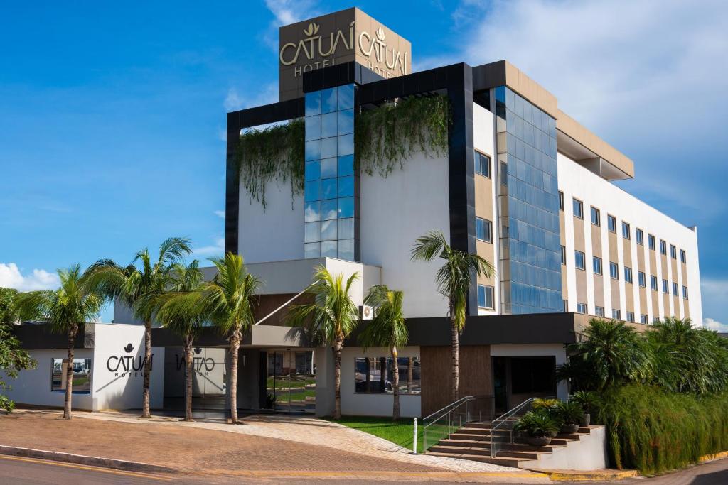 um edifício com palmeiras em frente em Catuai Hotel em Cacoal