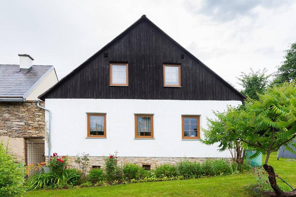 ein großes weißes Haus mit schwarzem Dach in der Unterkunft Poklidná Chalupa in Klenovice