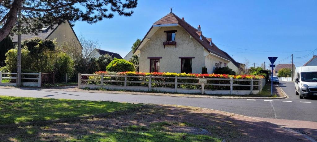 ein Haus mit einem Zaun mit Blumen davor in der Unterkunft Maison Colleville-Montgomery - Bord de mer in Colleville-Montgomery