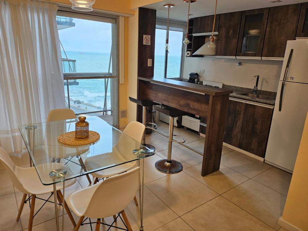 uma cozinha com uma mesa de vidro com cadeiras e um piano em Hermoso 2 ambientes en la costa con vista al mar em Mar del Plata