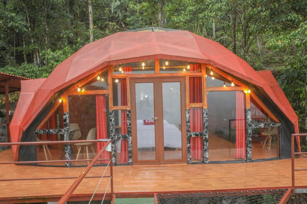 une maison ronde avec un toit rouge sur une terrasse dans l'établissement GLAMPING MINDO SUYANA, à Mindo