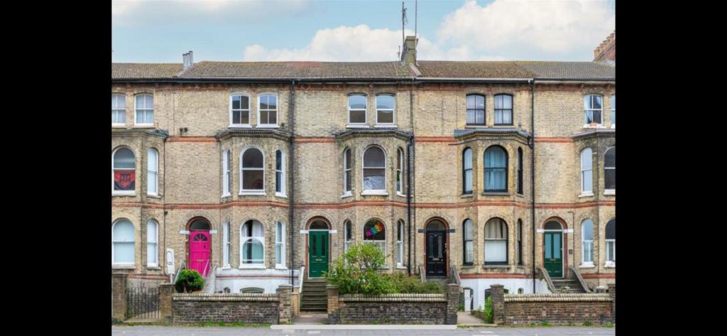 um grande edifício de tijolos com uma porta rosa em Spacious front bedroom - near The Level - 2 dogs live at the property em Brighton & Hove