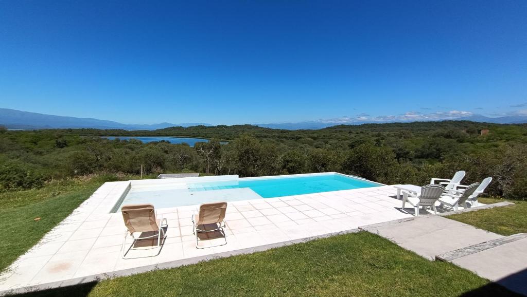 a swimming pool with three chairs and a swimming pool at Casa Paradiso in Coronel Moldes
