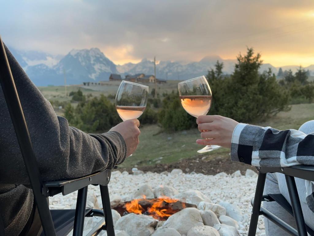 two people holding wine glasses in front of a fire at PeaksView Chalets in Žabljak