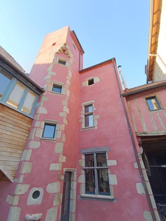 un bâtiment rouge avec une tour dans l'établissement Retrouvez votre famille ou vos amis au calme, à Aigueperse