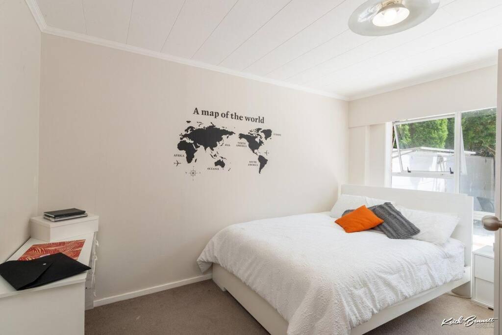 a white bedroom with a bed and a map on the wall at A modern 2 bedroom with private backyard, kitchen. in Lower Hutt