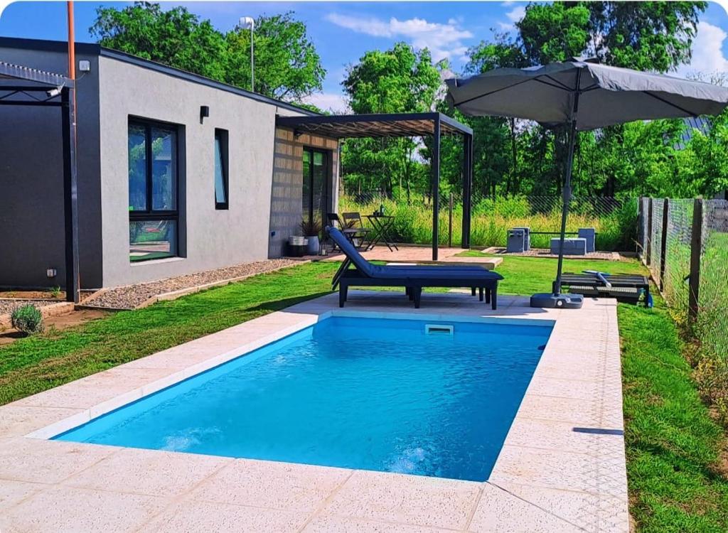 a swimming pool with a bench and an umbrella at Hada del Champaqui - Posada de Montaña in Villa General Belgrano