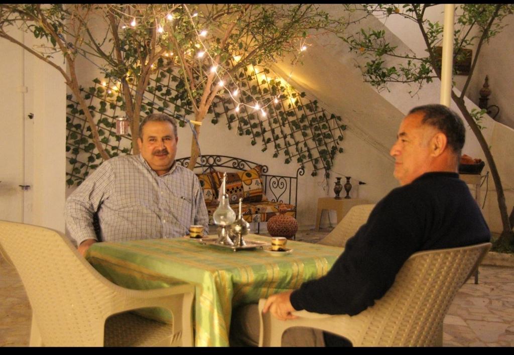 two men sitting at a table in a room at Henchir ejdoud in Kairouan