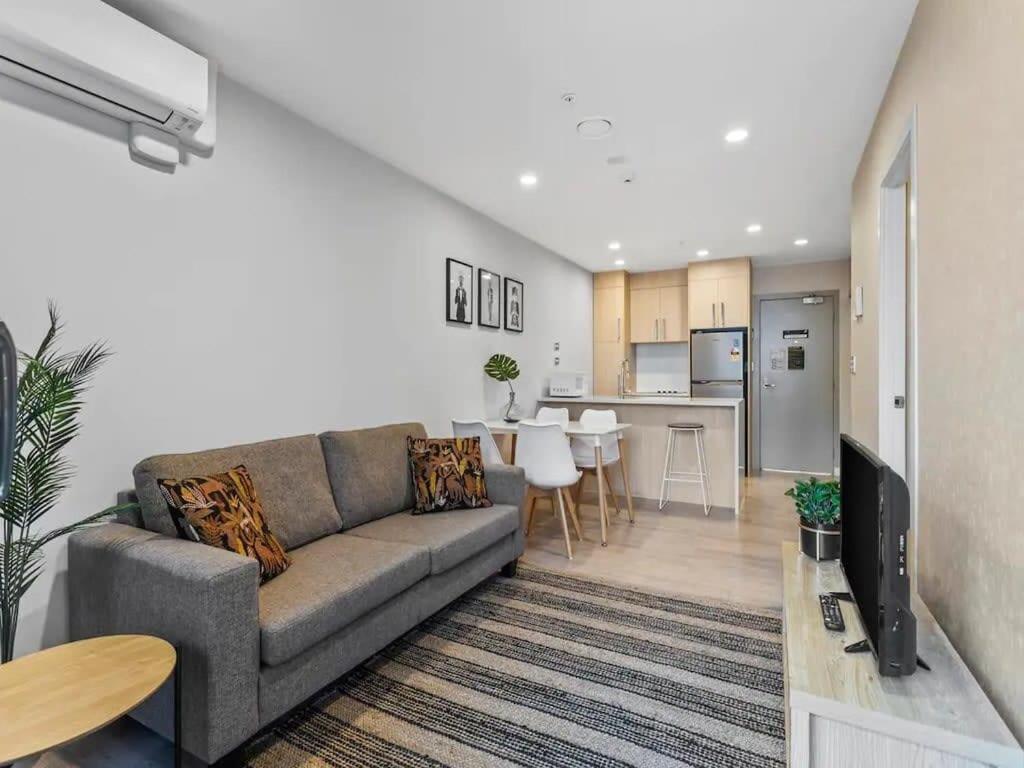 a living room with a couch and a kitchen at Stunning Apartment Amazing View near Sky Tower in Auckland