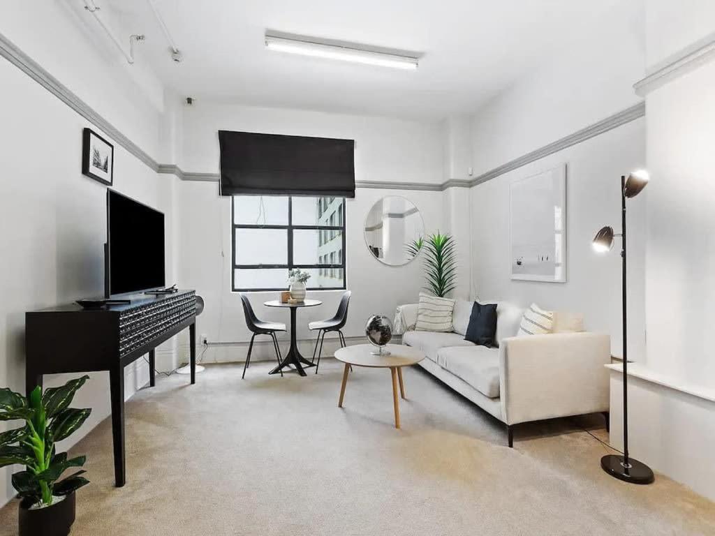 sala de estar con piano y sofá blanco en Lovely 1-Bedroom Unit in CBD by Zodiak Stays, en Auckland