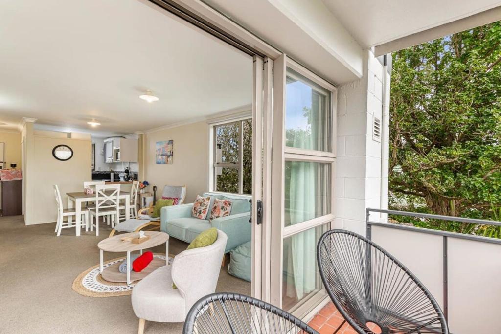 um quarto com uma varanda com um sofá e cadeiras em Lovely 2-Bedroom Apartment with Free Parking em Auckland