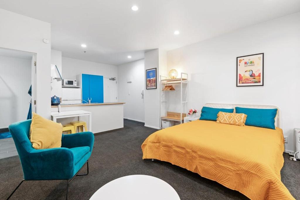 1 dormitorio con 1 cama y 1 silla azul en Cosy and central studio, en Auckland