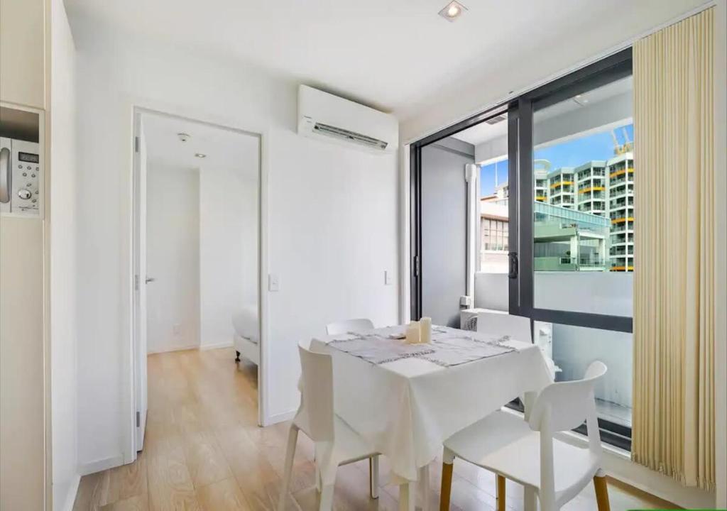 a white dining room with a white table and chairs at Central two-bedroom apartment close to Spark Arena in Auckland