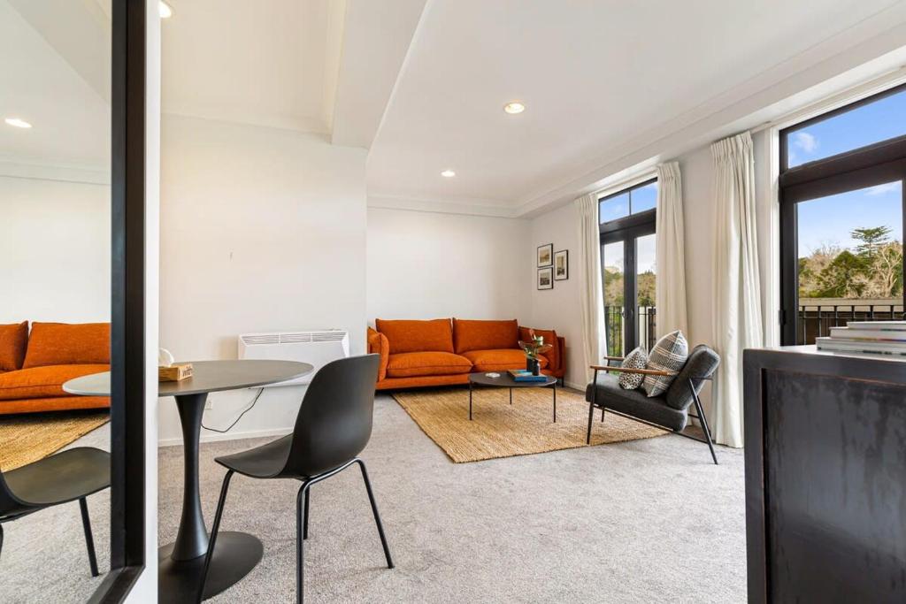 sala de estar con sofá naranja y mesa en Immaculate city-fringe apartment, en Auckland