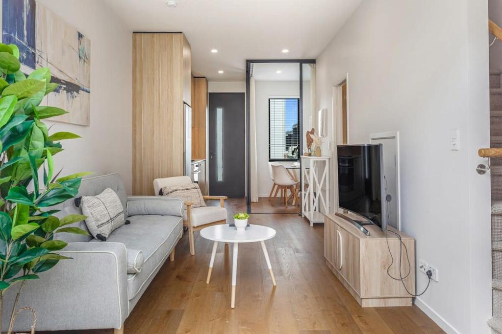 - un salon avec un canapé et une télévision dans l'établissement Fresh & sleek Grey Lynn unit with private patio, à Auckland
